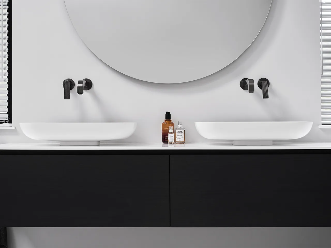 Badkamer met antoniolupi dubbele opzetwastafel op Rovere Grigio meubel Clou Kaldur wandkranen in Gun Metal ronde verlichte spiegel